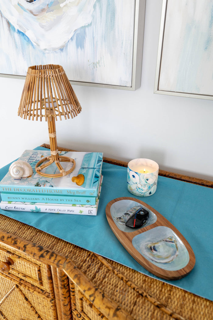 Oval wooden serving tray with oyster pattern atop a wicker table