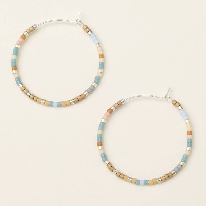 A pair of round earrings with a mix of desert blue and silver colors, made from brass nickel and cadmium-free hypoallergenic material.