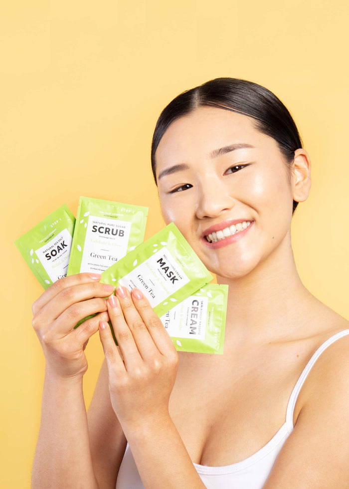 person holding up 4 step pedicure kit against yellow background