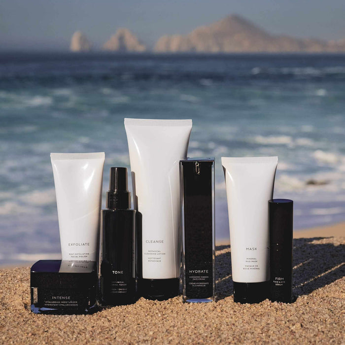 Skincare product set with white and black tubes, bottles and jar, including cleanser, exfoliant, mask and moisturizer