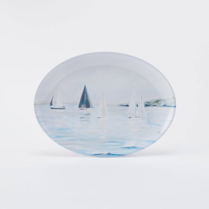 A round melamine platter with a printed design of sailboats on a blue background.