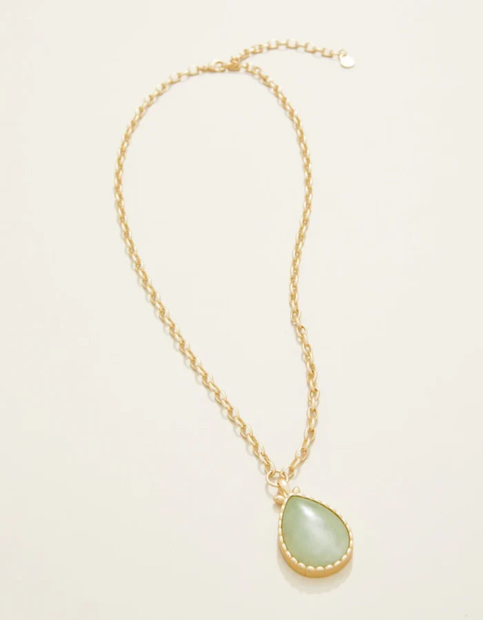 Necklace with a green teardrop pendant on a light beige background