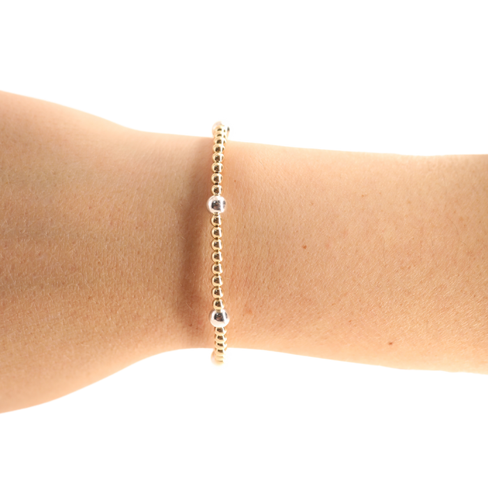 Gold bracelet on a wrist against a white background