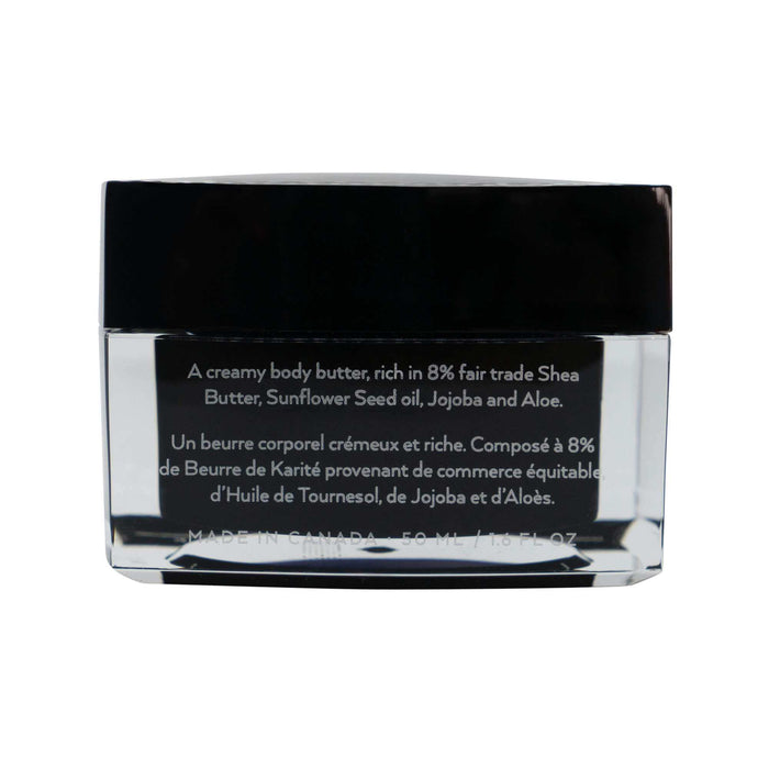 Shea Body Butter in a clear glass jar with a glossy black lid and white bilingual label detailing its ingredients