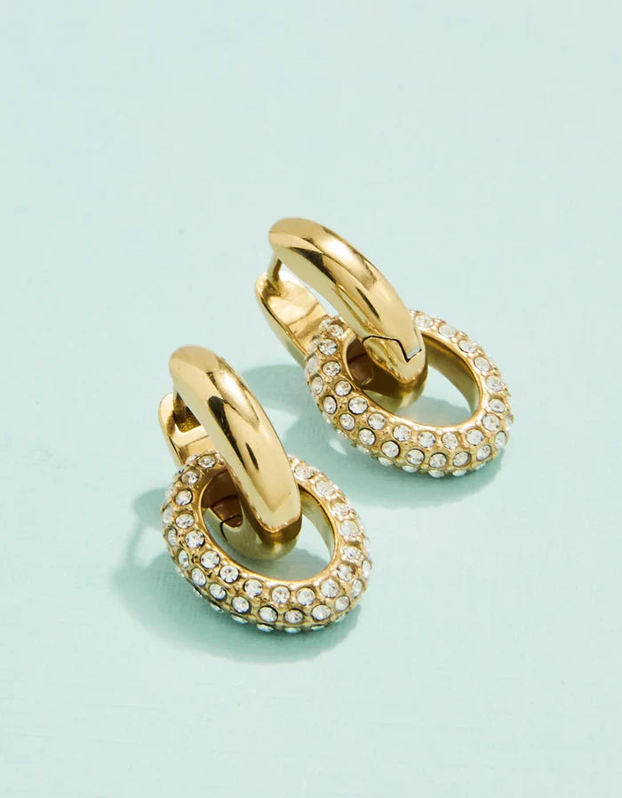 Gold hoop earrings with embedded stones on a light blue background