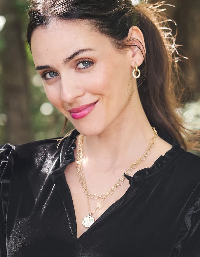 Woman wearing gold jewelry with a blurred natural background