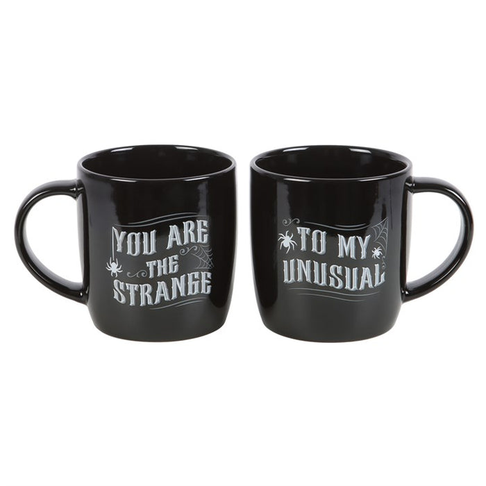matching gothic couple mugs shown together displaying you are the strange text
